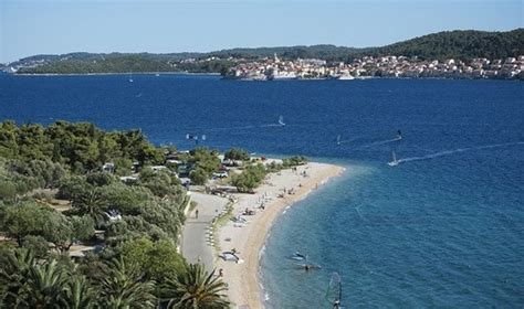 Prizor prodnate plaže s senco dreves v kampu