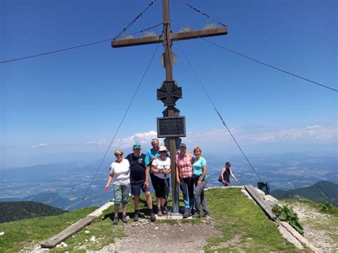 Pohodniki na vrhu slovenske gore s pogledom na dolino
