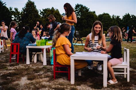 Slika nasmejanih ljudi, ki sedijo okoli mize na prostem