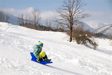Družina se sankanje na zasneženem hribu
