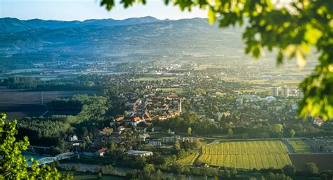 Panoramski pogled na podeželje Dolenjske z zelenimi griči in sadovnjaki.