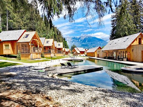 Panoramski pogled na glamping Ribno z lesenimi hiškami in naravnim bazenom.