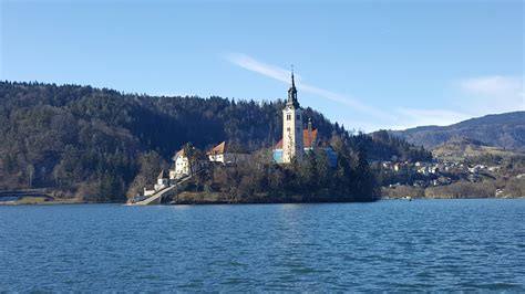 Blejski otok s cerkvico na sredini, obdan z jezersko vodo in zasneženimi gorami