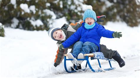 Otroci se sankajo na zasneženem hribu
