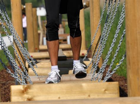 Otroci in odrasli preizkušajo ravnotežje na lesenih mostovih v MotorikParku Gamlitz.