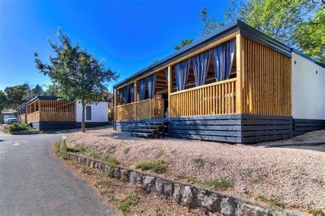 Skupina ljudi, ki uživa na terasi mobilne hišice s pogledom na zelene griče